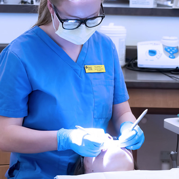 A student hygienist works on a client